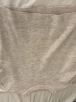 Beige stickad tröja från Gina Tricot - Mysig beige stickad tröja från Gina Tricot med kortare ärmar och rund hals. Tröjan har en avslappnad passform och ribbade muddar vid ärmslut och nederkant. Perfekt för lager-på-lager under kyligare dagar.