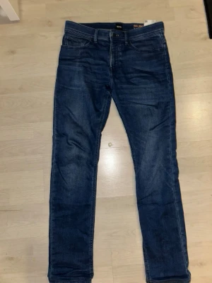 Mörkblå skinny jeans från Hugo Boss - Snygga mörkblå jeans från Hugo Boss med klassisk femficksdesign och läderpatch bak i midjan. Jeansen har en slim och skinny passform med raka ben och är tillverkade i mjukt denimtyg. Perfekta för dig som gillar stilrena och moderna jeans. Storlek 32/32