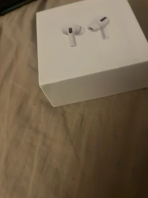 AirPods Pro - Säljer ett par Apple AirPods Pro i originalförpackning. Allt tillbehör medföljer: laddningsetui, laddkabel och extra öronproppar. Produkten ser ut att vara i mycket gott skick, perfekt för dig som vill ha trådlösa hörlurar med aktiv brusreducering och hög ljudkvalitet.