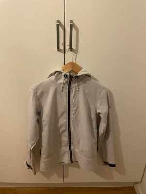 Vit vindjacka från Moncler med huva - Säljer en stilren vit vindjacka från Moncler med huva och dragsko. Jackan har hel dragkedja framtill, två sidofickor med dragkedja och Moncler-logga på ärmen. Perfekt för dig som vill ha en clean och sportig look.