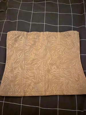 Beige mönstrad corsett från Maidenform - Säljer en beige väst från Maidenform med diskret zebramönster. Västen är rak i modellen och har elastiskt material som formar sig efter kroppen. Perfekt för dig som vill ha en clean look med lite extra edge.