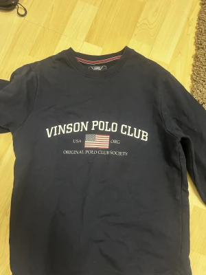 Vinson Polo Club sweatshirt storlek M - Två crewneck sweatshirts från Vinson Polo Club med tryckt logga och amerikansk flagga på bröstet. En är marinblå och den andra är grå, båda med rund hals och långa ärmar. Perfekt basic-plagg med college-vibe och skön passform. Säljer en för 150 båda för 200