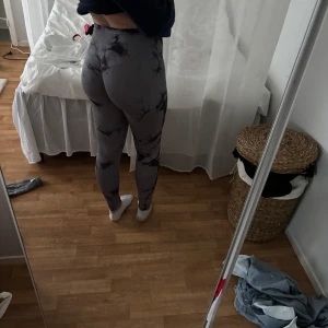 Grå-svarta mönstrade leggings - Säljer ett par grå leggings med svart marmorerat mönster. De är högmidjade och har en tight passform som sitter snyggt på kroppen. Perfekta för träning eller chill. Materialet är stretchigt och bekvämt.