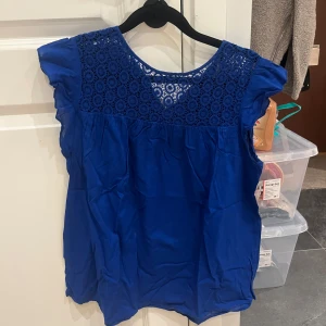 Blå blus med spets från Zara Basic - Supersöt blå blus från Zara Basic med rund halsringning och detaljerad spets upptill. Ärmlös modell med lätt volang vid axlarna och luftig passform. Perfekt för dig som vill ha en färgstark och feminin topp med fina detaljer.
