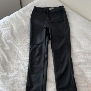 Svarta skinny skinnbyxor från ONLY - Säljer ett par svarta skinny skinnbyxor från ONLY med klassisk femficksdesign och normalhög midja. Byxorna har en tight passform och är tillverkade i ett stretchigt material som sitter snyggt och bekvämt. Perfekta för dig som gillar en stilren och enkel look.