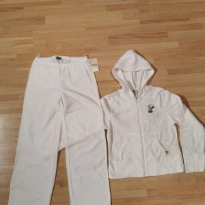 Vit hoodie med Snoopy från Seppälä - Vit hoodie från Seppälä med dragkedja och huva, tillverkad i mjuk polyester. På bröstet finns ett broderat Snoopy-motiv. Hoodien har långa ärmar och känguruficka framtill. Perfekt för dig som gillar en chill och söt stil.