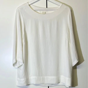 Vit blus med trekvartsärm - Stilren vit blus från H&M med rund halsringning och trekvartsärmar. Blusen har en rak passform och är tillverkad i ett tunt, lätt material som ger en luftig känsla. Perfekt för en clean och minimalistisk look.