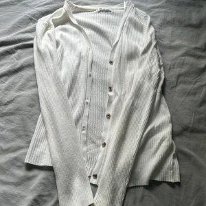 Vit ribbad kofta med knappar - Säljer en vit ribbad kofta från Cubus i storlek L. Koftan har långa ärmar, knappar framtill och är tillverkad i ett mjukt stickat material. Perfekt att slänga över en topp eller linne🥰 