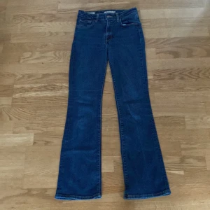 Levi's blå bootcut jeans - Snygga blå Levi's 725 jeans med klassisk bootcut passform och en hög midja. Jeansen har fem fickor, orange sömmar och den ikoniska Levi's-lappen bak. Tillverkade i slitstarkt denim med en mörkblå tvätt och detaljer som bälteshällor och knappgylf. 💞🫰🏻