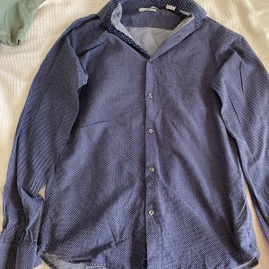 Jack & Jones premium skjorta slim blå - Slim fit skjorta från Jack & Jones i marinblå med små vita mönster. Krage och knappar framtill. Perfekt för festligheter eller bara för att vara lite extra stilig. 