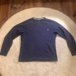 Marinblå långärmad tröja Polo Ralph Lauren - Säljer en marinblå långärmad tröja i strl S från Polo Ralph Lauren. Tröjan har ett diskret rutmönster i tyget och den klassiska broderade loggan på bröstet. Perfekt basic med rund hals och ribbade muddar. Hör av er vid fler frågor elr intresse 