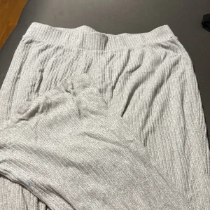 Grå ribbade mjukisbyxor - Mysiga grå mjukisbyxor med ribbad struktur och bred resår i midjan. Perfekta för chill dagar hemma eller när du vill vara extra bekväm. Byxorna har en avslappnad passform och är gjorda i ett mjukt material. 