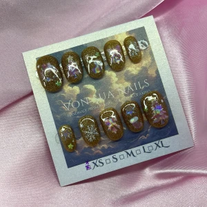 XmasSparkle (XS);Short Oval - *OBS! Mindre i storlek *Handgjorda press-on naglar i guld glitter bas med holografiska dekorationer som snöflingor, rosetter, stjärnor och julgranar. Naglarna har en kort oval form, lite mindre i storlek än en vanlig XS, och skimrar i olika ljus. Perfekt för dig som vill ha unika och festliga naglar med vinterkänsla.