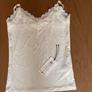 Vit spetslinne från Object XS/S - Supersött vitt linne i xs-s från vila/Object med tunna axelband och fin spets längs urringningen. Linnet är helt nyt med prislapp men som är av. Fick den igår och tog av prislappen utan att prova det och kan nu inte lämna tillbaka. 