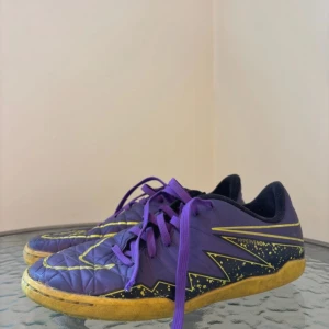 Nike Hypervenom lila inomhusfotbollsskor - Säljer ett par lila Nike Hypervenom inomhusfotbollsskor med gula detaljer och snörning. Skorna har en låg profil, platt gul sula och coolt mönster med svarta och gula inslag. Perfekta för dig som vill sticka ut på planen.