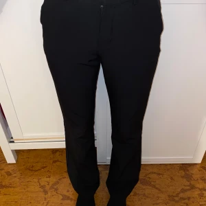 Svarta kostymbyxor från Bik Bok - Svarta kostymbyxor från Bik Bok med raka ben lite utsvängda och klassisk passform. Byxorna tillgång till bälte,  fickor fram och bak samt dragkedja och knapp i midjan. Perfekta för en clean och stilren look.