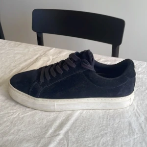 Mörkblåa mockaskor från Vagabond - Säljer ett par schyssta mörkblå mockaskor från Vagabond i mjuk mocka med klassisk vit sula. Det är storlek 39, men är ganska stora i storleken så passar upp till 40/41.  Skorna har rund tå, snörning och en clean look som passar till det mesta. Perfekta för dig som gillar minimalistisk stil och vill ha ett par bekväma skor till vardags.  Skorna är använda ett fåtal gånger och är i väldigt bra skick. Nypris är 1400 kr. Om du har några frågor eller funderingar är det bara att höra av sig! 