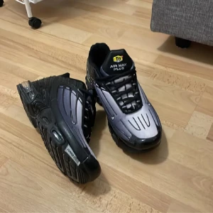Nike Air Max Plus 3 svarta och silver sneakers - Nike Air Max Plus sneakers i svart och silver med coola detaljer och Tuned Air-sula. Ovandelen har ett futuristiskt mönster och svarta snören. Snyggt Air Max Plus-tryck på plösen och robust yttersula för extra komfort. Perfekt för dig som gillar streetwear och sportig stil.