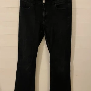 Svarta bootcut jeans Gina Tricot 170 - Svarta jeans från Gina Tricot i storlek 170. Modellen har bootcut-ben och klassisk femficksdesign. Jeansen är tillverkade i ett mjukt denimtyg och har normal passform med knapp och dragkedja framtill.