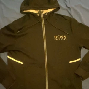 Svart Hugo boss tröja  - Svart Hugo boss hoodie med defekter på armbågarna och i luvvan