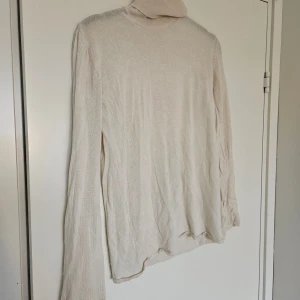 Vit polotröja i kashmir och silke - Supermjuk och tunn vit polotröja med lång ärm, tillverkad i lyxig mix av 70% kashmir och 30% silke. Fint skick, två små hål på baksidan men ena ihopsytt så syns knappt. Storlek L men skulle snarare säga den passar M