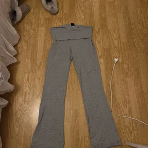 Grå yogapants från Gina Tricot - Grå yogapants från Gina Tricot med  utsvängda ben. Byxorna är i mjukt och stretchigt bomullsmaterial, perfekta för en chill och avslappnad look. Passformen är loose och de har en bred linning upptill. Byxorna är uppsydda men går lätt att åtgärda