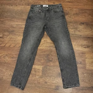 Mörkgrå/svart straight jeans från Pull&Bear - Snygga mörkgrå jeans från Pull&Bear i straight fit. Jeansen har klassisk femficksdesign, bälteshällor och en tvättad look som ger en cool vintagekänsla. Perfekta för dig som gillar en rak passform och stilren vibe.