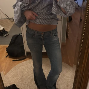 Blå bootcut jeans med normal passform - Säljer ett par klassiska blå jeans med bootcut-modell och normal passform. Jeansen har en lätt tvättad look och sitter snyggt i midjan. Perfekta för dig som gillar en tidlös stil med lite utsvängda ben. Materialet är jeans och färgen är mellanblå.