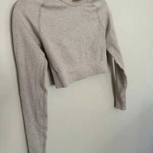 Beige ribbad croppad topp Aim'n - Säljer en beige ribbad croppad topp från Aim'n i storlek S. Toppen har långa ärmar, rund halsringning och är tillverkad i ett mjukt, stretchigt material som sitter snyggt på kroppen. Perfekt för en trendig och avslappnad look.