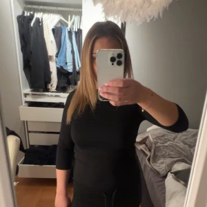 Svart tight trekvarts ärmad tröja  - Säljer en svart långärmad tröja med tight passform och rund hals. Tröjan är enkel och stilren, perfekt att matcha med olika outfits. Materialet känns mjukt och följsamt mot kroppen.