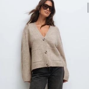 Beige kofta med knappar och fickor - Säljer en slutsåld kofta från Gina helt ny med prislappen kvar . Beige, stickad kofta med v-ringning och tre stora knappar framtill. Koftan har två framfickor och ribbade muddar vid ärmslut och nederkant. Passformen är loose och ärmarna är långa, perfekt för lager-på-lager under höst och vinter.