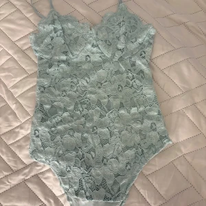 Body  - En ljusgrön/mintgrön body med mönster, v-ringning och tunna, smala band. 