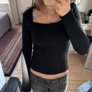 Svart ribbad topp från Gina Tricot - Säljer en svart, ribbad långärmad topp från Gina Tricot. Toppen har en fyrkantig ringning och är figurnära med stretchigt material. Perfekt att styla med jeans eller kjol. 