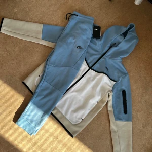 Nike hoodie i blått och vitt - Nike tech tracksuit aldrig använt ( Endast prövat den på) Fick den som present men är tyvärr storlek M och jag bär L. Priss lapp fortfarande på.