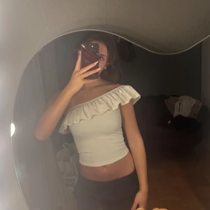 Vit one shoulder volang topp - Säljer en vit, one shoulder topp från H&M i stretchigt material. Kan både klä upp och ner toppen, älskar! Säljer då den inte kommer till användning, använd 1 gång. Bra material. 