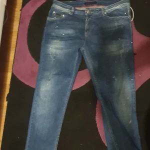 Blå Diesel jeans SLMFT 028 W36 L34 - Snygga blå jeans från Diesel, modell SLMFT 028. Jeansen har klassisk femficksdesign, raka ben och coola slitningar framtill. Tillverkade i 100% bomull med tydliga tvättade detaljer och kontrastsömmar. Perfekta för en avslappnad streetstil.