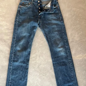 Helt nya Levi's 501 blå jeans W30 L32 - Klassiska Levi's 501 jeans i blå denim med raka ben och knappgylf. Snygg vintagekänsla och ikonisk läderpatch bak. Perfekta för dig som gillar tidlös stil och vill ha ett par jeans som funkar till allt.
