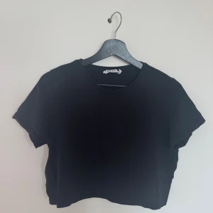 Svart croppad t-shirt från NA-KD - En svart croppad / kortare t-shirt från NA-KD med rund halsringning och korta ärmar. 