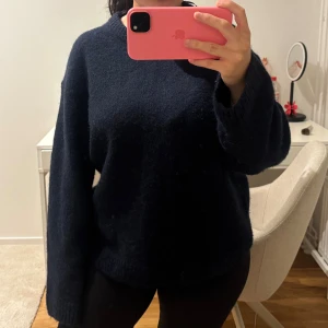 Mörkblå stickad tröja Gina Tricot - Mysig mörkblå stickad tröja från Gina Tricot i storlek S. Tröjan har en loose passform med långa ärmar och ribbade muddar vid hals och ärmslut. Perfekt för kyliga dagar och enkel att matcha med jeans eller leggings. Knappt använd, det är deras "crew neck knitted sweater" Material 	Acrylic 52%, Polyester 25%, Ull 14%, Alpackaull 7%, Elastan 2%