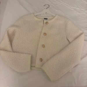 vit kofta med guldknappar - Elegant vit kofta från Gina tricot. Med dekorativa guldknappar. Koftan har en fluffig material. Passformen är normal och den är långärmad, perfekt för att ge en chic touch till din outfit.💕😚✌️