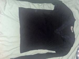 Svart långärmad topp med spets Gina Tricot - Svart långärmad topp från Gina Tricot med snygg v-ringning dekorerad med spetsdetaljer. Toppens material känns mjukt och stretchigt, perfekt för en stilren look. Passformen är normal och toppen är enkel att matcha med olika outfits.