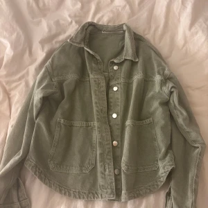 Grön jeansjacka - Snygg ljusgrön jeansjacka med klassisk krage och stora fickor framtill. Jackan har silverfärgade knappar och är tillverkad i ett slitstarkt bomullsmaterial. Perfekt att slänga över en hoodie eller t-shirt för en chill look.