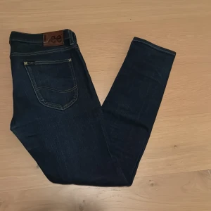 Mörkblåa jeans från Lee - Snygga mörkblå jeans från Lee med klassisk femficksdesign och kontrastsömmar. Jeansen har en läderpatch med Lee-logga bak och är tillverkade i slitstarkt jeansmaterial. Perfekt passform och stilren look.