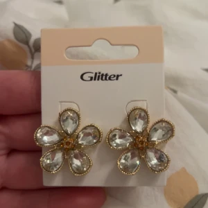 Blommiga örhängen  - Superfina örhängen i form av blommor med stora, glittriga kristaller och guldfärgade detaljer. Nya aldrig använda jättefina men dom kommer nog inte komma till användning därför säljer jag💕