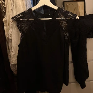 Svart blus med spetsdetaljer - Svart blus med transparenta spetsdetaljer över axlar och bröst från CUBUS