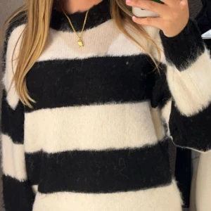 Svartvit randig stickad tröja - Mysig stickad tröja med breda svarta och vita ränder. Tröjan har långärmade och en loose passform som ger en chill vibe. Perfekt för dig som gillar en enkel men ändå cool stil. Materialet är fluffigt och mjukt, vilket gör den extra skön att ha på sig. Första två bilderna är från när den var ny, den sista är mer ”accurret” i hur den ser ut, alltså nopprig💕