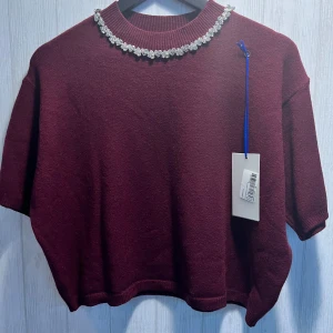 Sweater - one size -högt kvalitet  - Elegant short-sleeve knit top with a relaxed fit Features a delicately beaded neckline for a refined, feminine touch Soft knit texture offers comfort and light warmth Ribbed neck, hem, and sleeves maintain a structured shape Perfect for elevating casual looks or pairing with tailored bottoms.