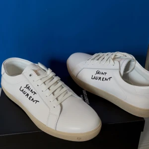 Saint Laurent vita sneakers i skinn - Tjena, säljer mina helt oanvända saint lauren skor. Fick när jag fyllde år men passade inte riktigt mina fötter. Skriv vid minsta frågor och priset kan diskuteras. Alla förslag bemöts❤️💯 De är lite små i storleken Handskriven logga på sidan. Skorna har rund tå, platt sula i beige ton och klassisk snörning. Kan inte garantera att de är äkta så det är mycket möjligt att få skorna billigare.