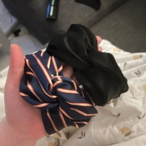2-pack hårband, svart & en randigt - Två stycken fina hårband i silke material. Bra stretch (i själva bandet som syns på bilden). (En från Gina tricot o en från hm) den som är randig är mörkblå i grunden med röd&vita ränder.