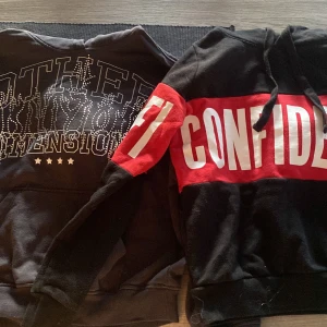 Svarta hoodies med tryck XS/XXS - Två snygga hoodies i svart, en från H&M Divided med silvriga nitar och texten 'Other Dimension', och en från FB Sister med röd och vit tryckdetalj 'CONFIDENCE' över bröstet och ärmen. Båda har huva och snörning, perfekt för dig som gillar statement-plagg.